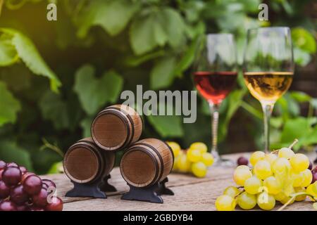 Winery concept. Miniature wine barrels on the wooden background of vineyards, grape, and wine glasses with red and white wine. Selective focus, copy Stock Photo
