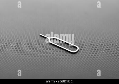 sim card ejector tool on black texture background Stock Photo