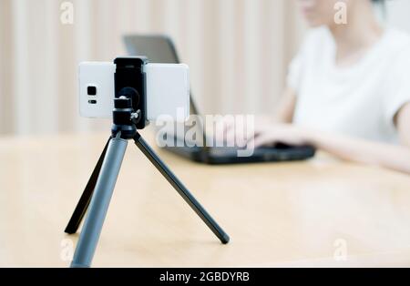 Woman vlogger looking using laptop computer and filming on video her life Stock Photo