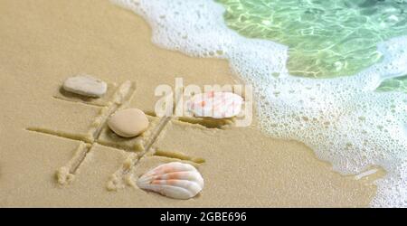 Soft wave with foam, a tic tac toe game drawn in the sand on the beach Stock Photo