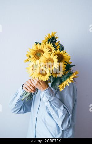 Young pretty woman holding a bouquet of sunflowers on a white background. Floral minimal composition. High quality photo Stock Photo