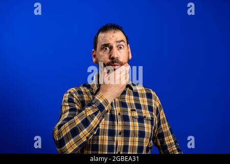 Handsome middle age senior man with grey hair over isolated blue background with hand on chin thinking about question, pensive expression. Smiling and Stock Photo