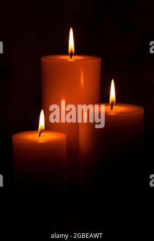 Three Pillar Candles Lit in a Dark Room Stock Photo