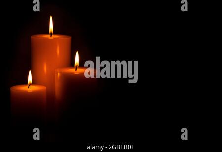 Three Pillar Candles Lit in a Dark Room Stock Photo