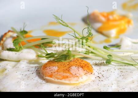 Fried sunny side up eggs with green garnish and black pepper. Stock Photo