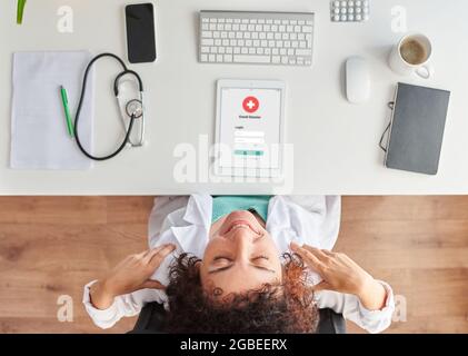 Top view of a female doctor stretching sitting at the desk in her medical office Stock Photo