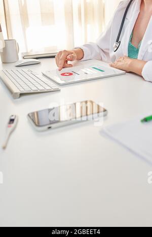 An unrecognizable female doctor uses her digital tablet Stock Photo