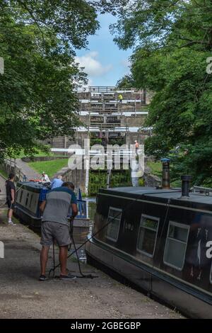 A man moors up his barge (narrowboat) on the Leeds Liverpool Canal at the bottom of the Five Rise Locks in Bingley, Yorkshire. Stock Photo