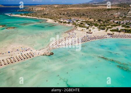 Aerial view of sunshades and umbrellas on a narrow sandy beach surrounded by shallow lagoons (Elafonisso Beach, Crete, Greece) Stock Photo