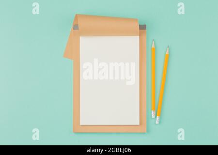Open notepad with pencil on cyan background. Stock Photo