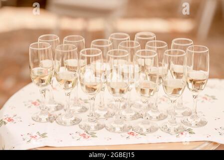 Champagne flutes half full with a bubbly fizzy alcoholic drink set on a large trey, sparkling wine in long glasses prepared for the wedding guests Stock Photo