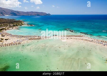 Aerial view of sunshades and umbrellas on a narrow sandy beach surrounded by shallow lagoons (Elafonisso Beach, Crete, Greece) Stock Photo