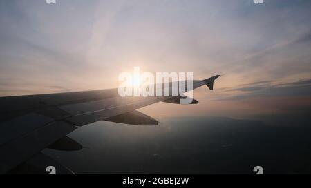 View from the porthole to the wing of the aircraft in flight. Sun and clouds over the wing of the aircraft at altitude. High quality photo Stock Photo