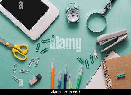 School set with notebooks, pens, laptop, scissors, stapler, magnifying glass on a blue background. Back to school concept. template for design Stock Photo