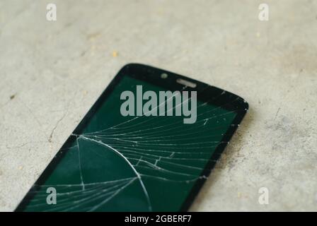Closeup shot of a shattered mobile phone screen with cracks Stock Photo