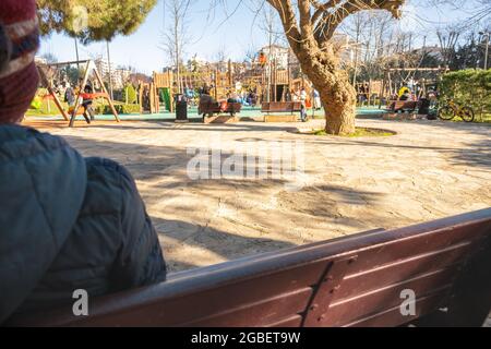 Kadikoy, Istanbul, Turkey - 02.03.2021: an unrecognizable cold child looks at people playing in Kadikoy freedom park with copy space Stock Photo