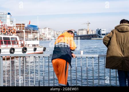 Eminonu, Istanbul, Turkey - 02.18.2021: municipal employees resting and looking at sea in coastal area of Eminonu after taking break with copy space