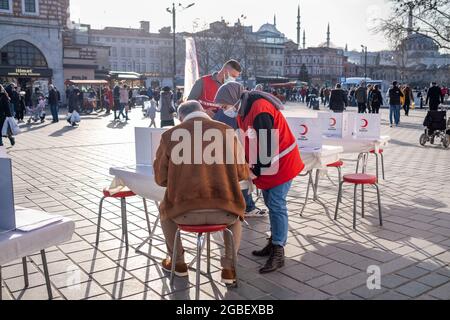 Eminonu, Istanbul, Turkey - 02.26.2021: blood donation volunteers signs checklist and Turkish Red Crescent (Turk Kizilay) employees helps them in Emin Stock Photo