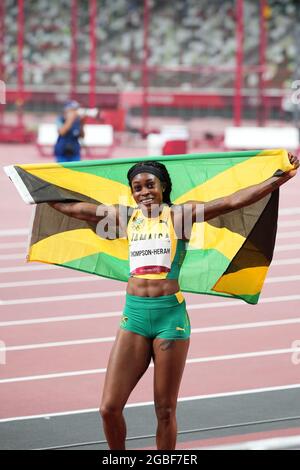 3rd August 2021; Olympic Stadium, Tokyo, Japan: Tokyo 2020 Olympic summer games day 11; Womens 200m final; THOMPSON-HERAH Elaine of Jamaica with national flag as she wins the race and gold medal Stock Photo