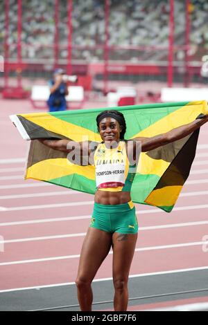 3rd August 2021; Olympic Stadium, Tokyo, Japan: Tokyo 2020 Olympic summer games day 11; Womens 200m final; THOMPSON-HERAH Elaine of Jamaica with national flag as she wins the race and gold medal Stock Photo