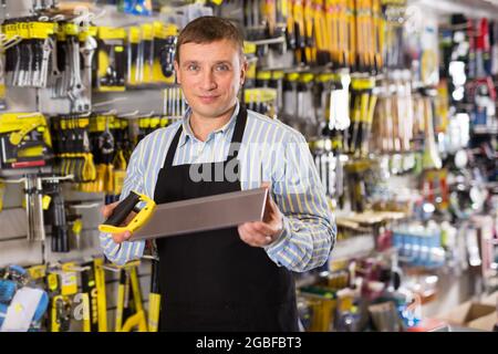 Man seller in apron having tools in hands Stock Photo