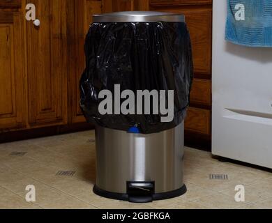 A Stainless Steel Garbage Can With a Black Plastic Trash Bag Stock Photo