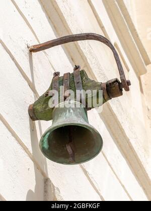 An antique old metal vintage bell mounted on the wall. Stock Photo