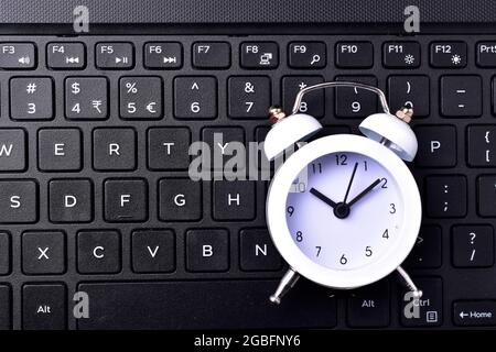 clock on keyboard concept for time management and countdown to deadline Stock Photo