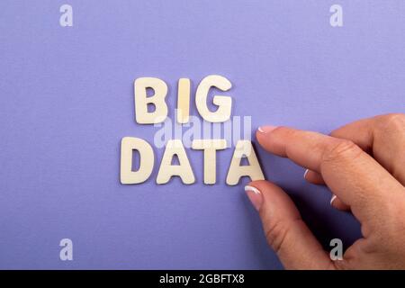 BIG DATA. White wooden letters with text and a woman's hand on a purple background. Stock Photo