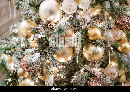decorated with golden balls and transparent icicles, the branches of the Christmas tree in the evening light Stock Photo