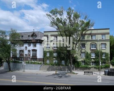 Old style small low rise apartment buildings on a main street, covered in vines Stock Photo