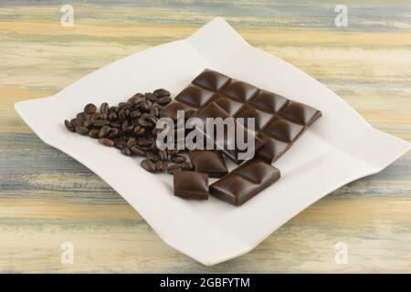 Coffee flavored dark chocolate with coffee beans on white snack dessert plate Stock Photo