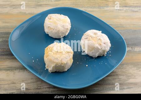 Greek almond kourabiedes cookies on blue dessert plate on table Stock Photo