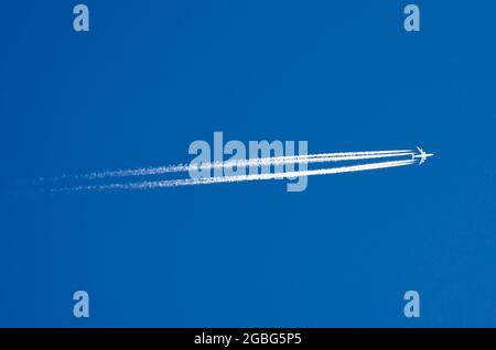 Large passenger liner and trail from an airplane in a blue sky Stock Photo