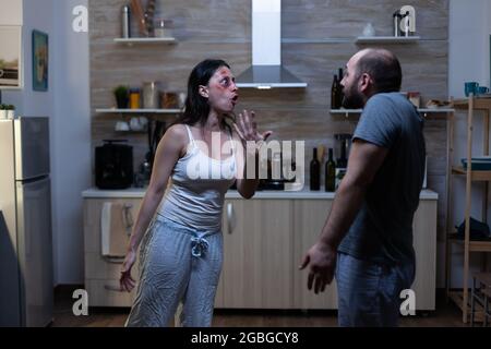 Furious husband and wife shouting and arguing having social marriage problems. Violent aggressive man yelling at bruised angry woman, couple dealing with domestic violence and conflict Stock Photo