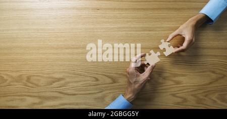 business strategy, solutions and teamwork concept. people connecting jigsaw puzzle pieces on wooden table background. banner copy space Stock Photo