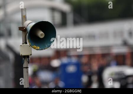A weathered megaphone, public address speaker with pit lanes in the background Stock Photo