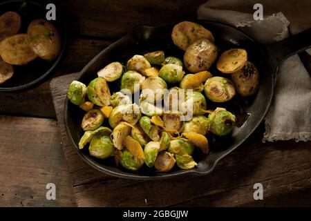 High angle of pan with yummy vegan dish of cut brussels sprouts and unpeeled potato pieces on cutting board Stock Photo