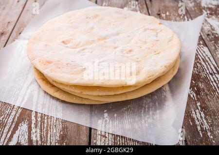 Flatbread, pita or pizza crust on wooden kitchen table Stock Photo