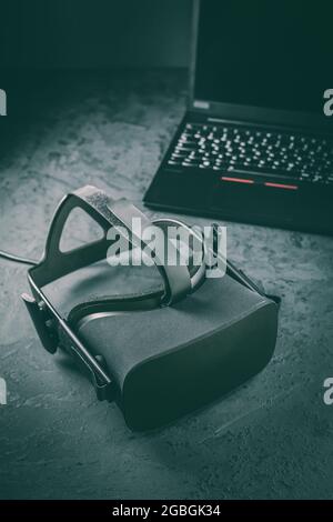 VR headset - virtual reality glasses for simulation of reality for different multimedia with laptop in background Stock Photo