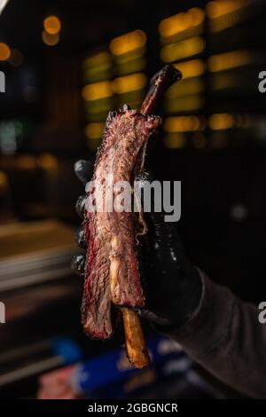 Man's hand in black glove holding an appetizing steak Stock Photo