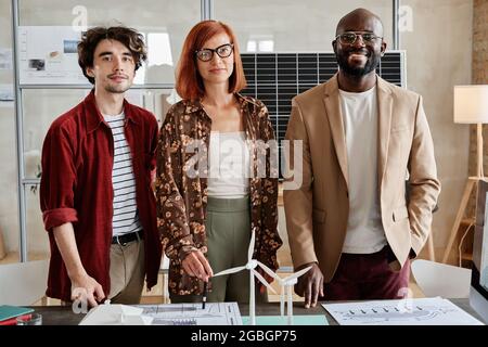 Portrait of successful group of architects smiling at camera while standing at the table with architectural models at office Stock Photo