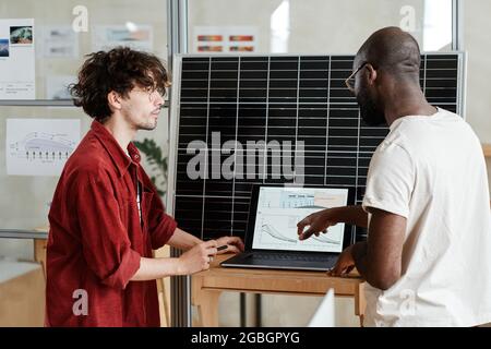 Two designers sitting at the table in front of laptop and developing new project online at office Stock Photo