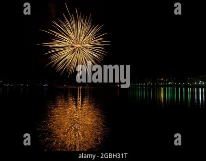 night illuminated by fireworks display on Lake Lugano for August 15th, Porto Ceresio, Lombardy, Italy. Stock Photo