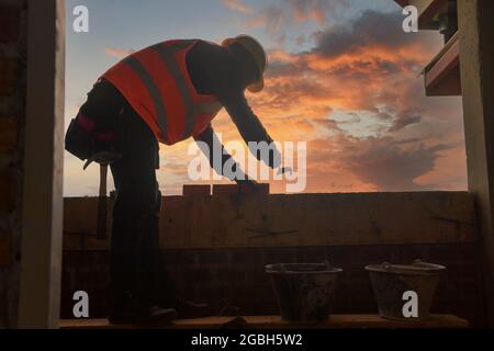 Bricklayer building a wall on a construction site, Thailand Stock Photo