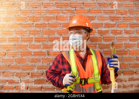 Portrait of a construction worker wearing a protective face mask, hard hat and reflective clothing, Thailand Stock Photo