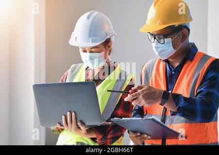 Two architects standing in an office looking at a laptop Stock Photo