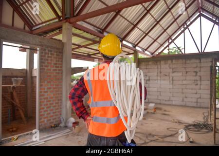 Construction worker carrying pipe on his shoulder Stock Photo - Alamy