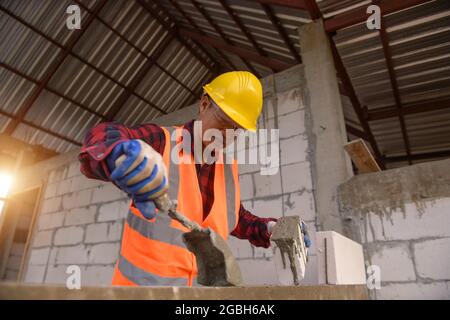 Bricklayer building a wall on a construction site, Thailand Stock Photo