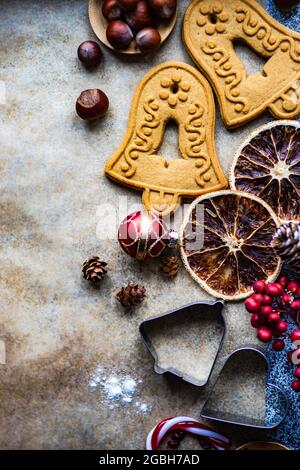 Christmas bell cookies, cookie cutters, nuts, dried fruit and Christmas decorations on baking paper Stock Photo
